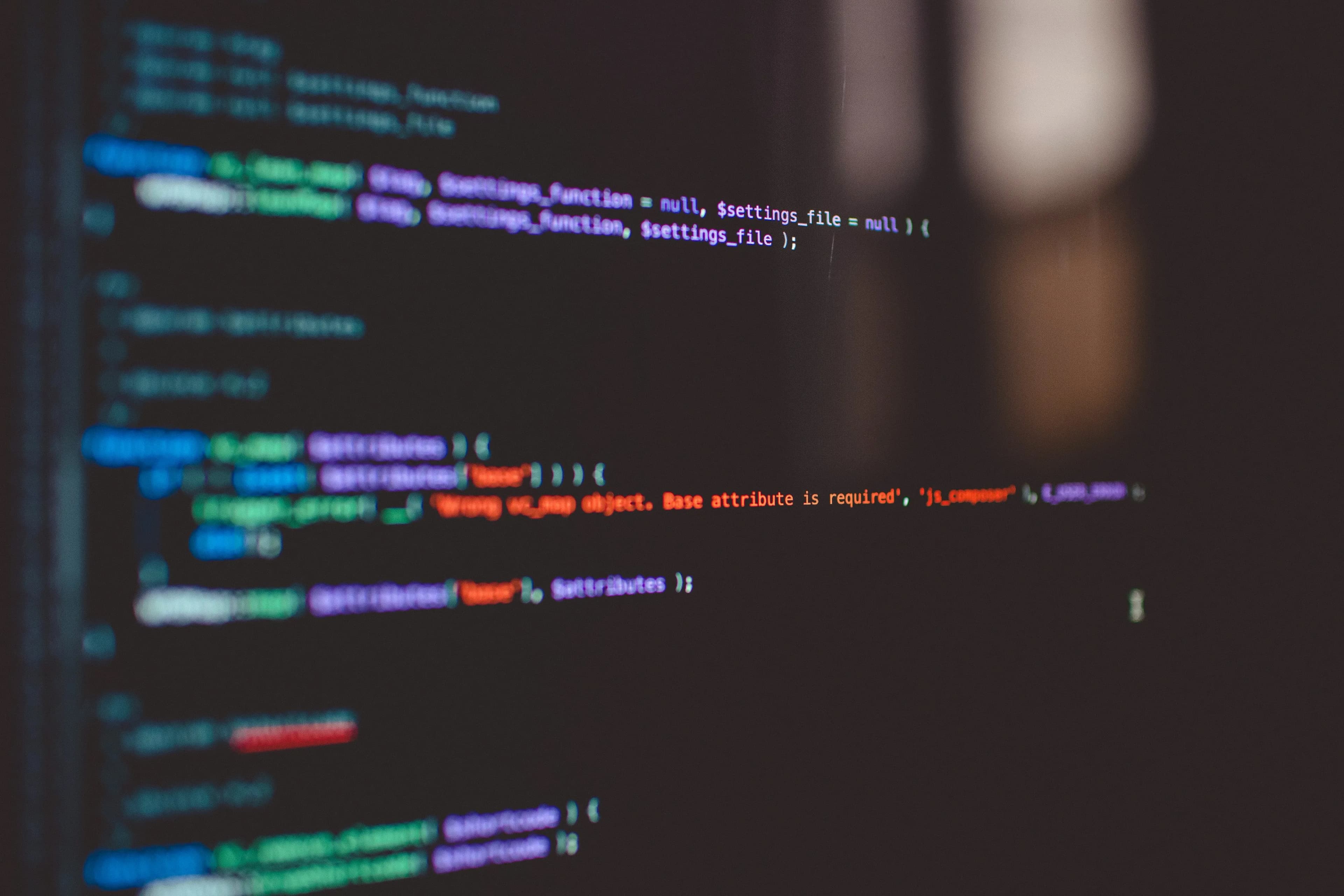 Close-up of a computer screen displaying colorful lines of code on a dark background.